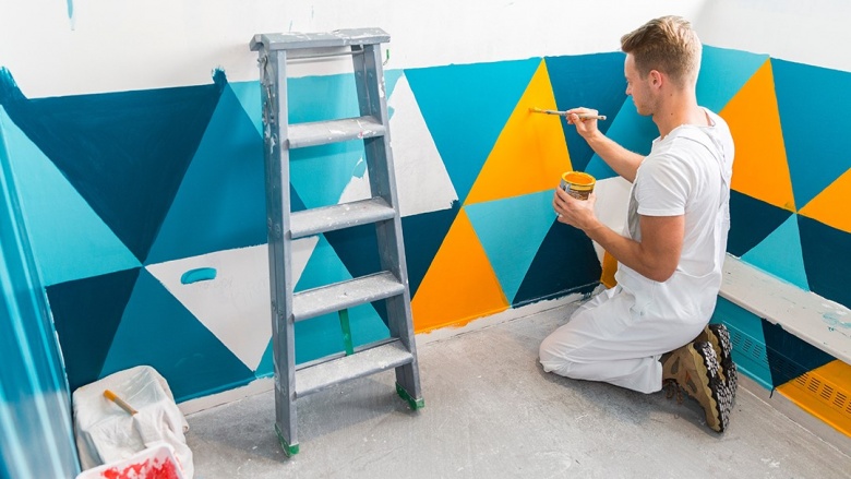 Im Dialog mit dem Handwerk: Im Austausch mit Ausbildungsförderung und Haushaltskürzungen mit der Innung Mettmann Maler malt Muster an Wand in Gelb, Türkis und Blautönen.