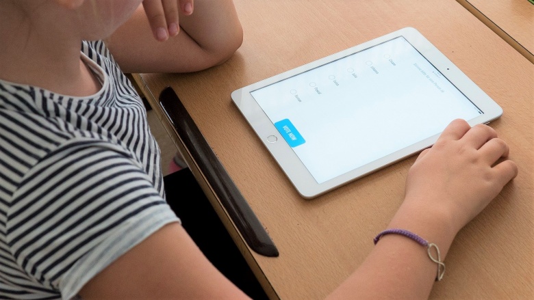 Kind mit einem Tablet bearbeitet digital eine Multiple-Choice-Aufgabe.