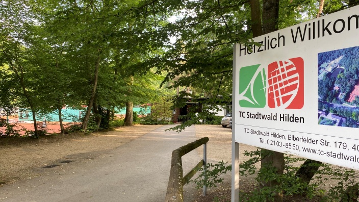 Draußen am Eingangsbereich des TV Stadtwald Hilden mit einer "Herzlich Willkommen"-Tafel.